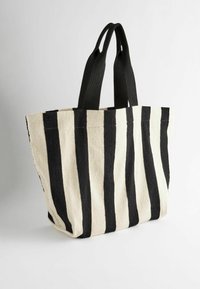 Canvas draagtas met afwisselend zwarte en crème verticale strepen, voorzien van stevige zwarte nylon handvatten. Gestructureerde vorm, duurzame textuur.
