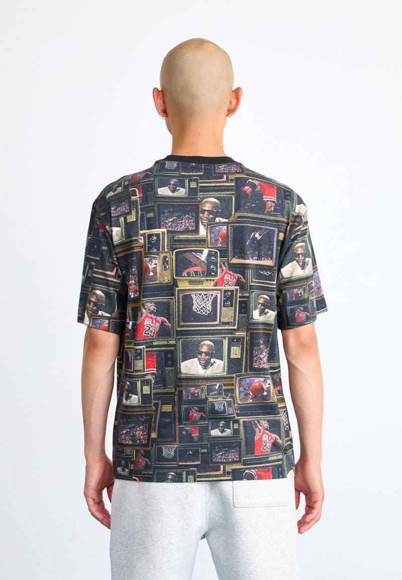 T-shirt à manches courtes présentant un collage de téléviseurs rétro avec des images de basketball, principalement dans des tons de noir, rouge et vert.