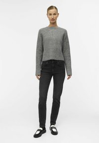 Hallide kudum sweater pika varrukatega, kombineeritud mustade kitsaste teksade ja mustade loafereitega, millel on valged aktsendid.