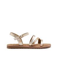 Sandal in metallo dorato con due cinturini diagonali, un cinturino alla caviglia e una suola marrone texturizzata con piccoli motivi rotondi.