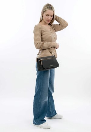 Schwarze Handtasche mit goldenen Akzenten, rechteckiger Form und abnehmbarem Tragegurt, kombiniert mit einem beigen gerippten Cardigan und hellblauen Jeans.