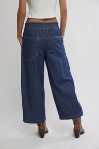 Τζιν παντελόνι με φαρδιά μπατζάκια και ελαστική μέση, με δύο πίσω τσέπες και αντίθετη ραφή. Το ύφασμα είναι μεσαίου σκούρου μπλε χρώματος.