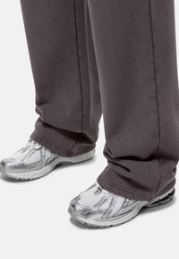 Gray sweatpants with a smooth texture, paired with silver athletic shoes featuring a mesh design and a cushioned sole.