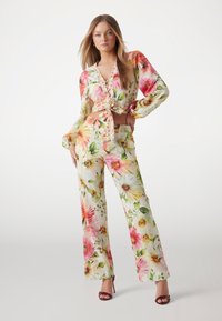 Bloemrijke twee-delige set met een cropped blouse met striksluiting aan de voorkant en lange mouwen, en een hoge taille met wijde pijpen in een kleurrijk bloemenpatroon.