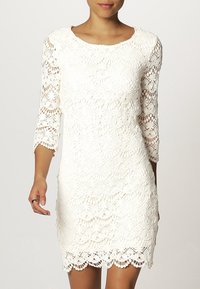 Vitt spetsklänning med trekvartsärmar, scallop-mudd och intrikata blommönster över hela tyget.