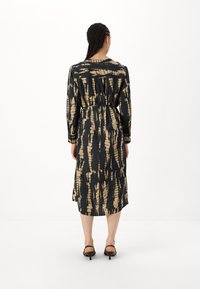 Juosmens ilgio juoda suknelė su auksine abstrakčia tekstūra, ilgomis rankovėmis ir sugriežtintu juosmeniu. Minkšta medžiaga su lygiu paviršiumi ir apvaliu iškirpimu.