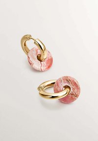 Pendientes de aro de metal dorado con un acento de piedra redonda mármol rosa. La piedra presenta remolinos de tonos rosa más claros y más oscuros. Textura suave.