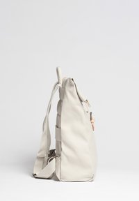 Ljusbeige ryggsäck i mjukt, texturerat material, med dragkedjestängning, justerbara axelremmar och en sidoficka med ett spänne.