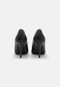 Scarpe col tacco alto in pelle nera con design a punta, texture liscia e silhouette elegante. Presentano un sottile tacco a stiletto.