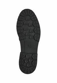 Black rubber shoe sole featuring a textured, patterned tread with hexagonal protrusions and ridges for grip and traction.
