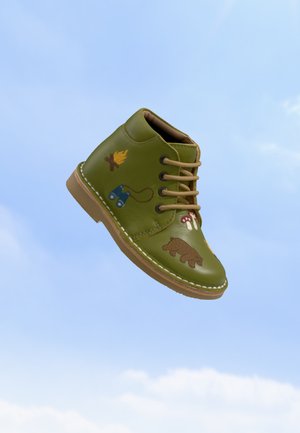 Green children's ankle boot with brown sole and laces, decorated with images of a bear, campfire, binoculars, and mushrooms.