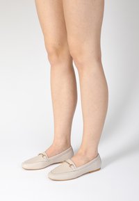 Beige leren instappers met een gladde textuur en een goudkleurig accent. Ronde neus en laag profiel ontwerp, ideaal voor casual outfits.