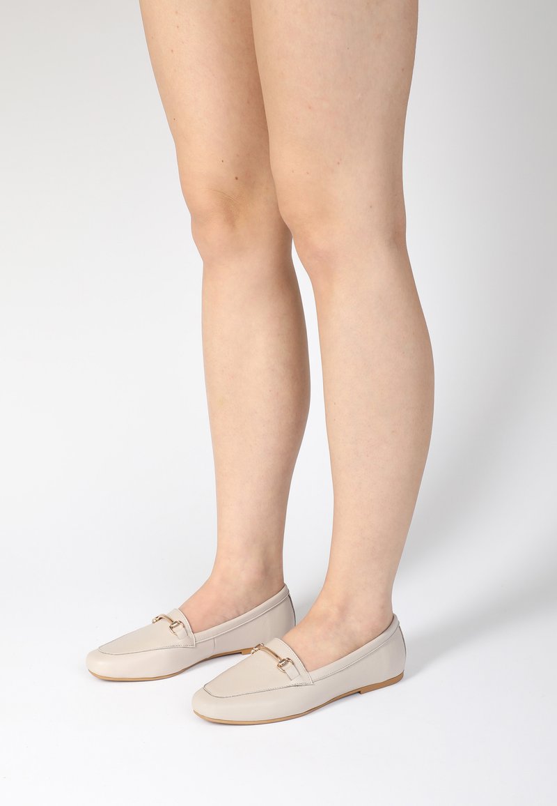 Beige leren instappers met een gladde textuur en een goudkleurig accent. Ronde neus en laag profiel ontwerp, ideaal voor casual outfits.