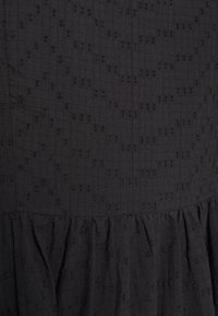 Svart klänning med ett strukturerat rutmönster och subtila upphöjda detaljer, volangkjol och lätt tyg.