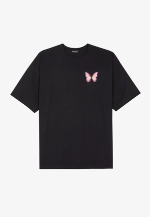 T-shirt noir à manches courtes avec un petit motif papillon rose et jaune sur le côté gauche de la poitrine.