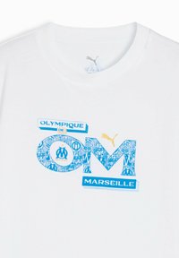 Valge T-särk, millel on sinine ja kuldne "Olympique de Marseille" kujundus dekoratiivsete tähtedega ja Puma logo.