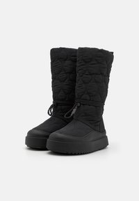 Bottes noires matelassées avec une surface texturée, de forme haute et semelle en caoutchouc. Présentent une fermeture à cordon et une épaisse semelle en plateforme.