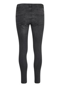 Jeans negros ajustados con una textura suave, diseño de cinco bolsillos y detalles de costura sutiles en la cintura y los bolsillos.