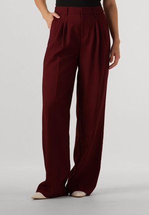 Weite Hosen aus bordeauxfarbenem Stoff mit Falten, flachem Bund und Seitentaschen. Glatte Textur und lockere Silhouette.