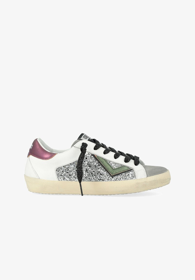 Sneaker bas blanc avec lacets noirs, panneau latéral en paillettes argentées, détail en chevron vert, embout gris et talon violet métallisé.