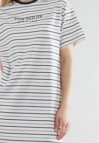 Vestito a tunica a righe bianco con strisce navy, dotato di colletto rotondo, maniche rilassate e logo "Tom Tailor" nella zona del petto.