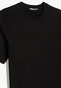 Sort bomulds T-shirt med rund hals, korte ærmer og en tætsiddende pasform. Glat tekstur med pæne stikninger og et mærke ved halsudskæringen.