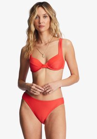 Crveni bikini set s rebrastom teksturom, grudnjak s žicom i širokim trakama, te odgovarajući visoki donji dio s glatkom završnom obradom.