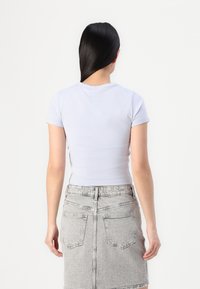  Lichtblauw, kort shirt met aansluitende pasvorm, gecombineerd met een hooggesneden grijze denim rok met achterzakken en een textuurafwerking.