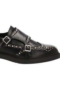 Zapato de cuero negro con adornos de tachuelas plateadas, cierres de doble hebilla y punta redondeada. Superficie texturada con costuras en contraste.