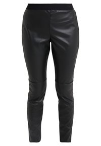 Pantalons en simili cuir noir avec une texture lisse, coupe fuselée et taille élastique. Présente un motif matelassé au niveau des genoux.
