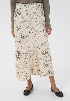 Jupe maxi en tissu doux, avec un motif beige et marron moucheté. L'ourlet est évasé, associée à des chaussures plates noires.