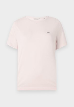 Hele-roosa puuvillane t-särk ümarselja kaelusega, lühikeste varrukatega ja väikese logoga rinnal. Sile tekstuur, lihtne disain.