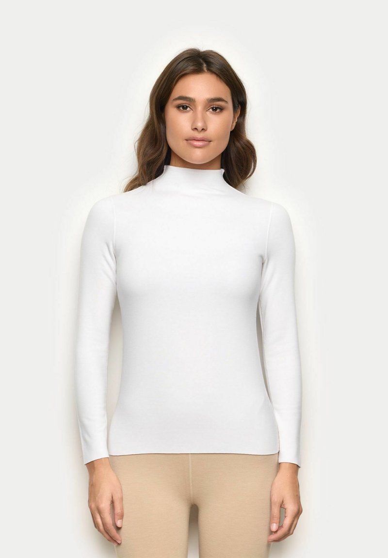 Weiße Langarm-Turtleneck-Oberteil mit figurnaher Passform und glatter Textur, kombiniert mit hellbeigen Leggings.