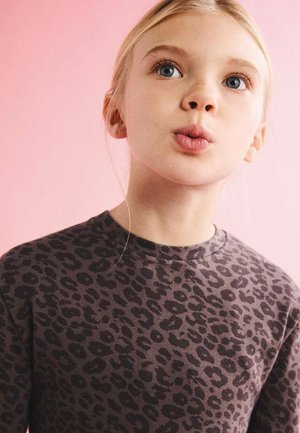 Sweat-shirt marron à imprimé léopard avec un col rond. Le tissu semble doux avec une légère élasticité. Le fond est d'une couleur rose uni.