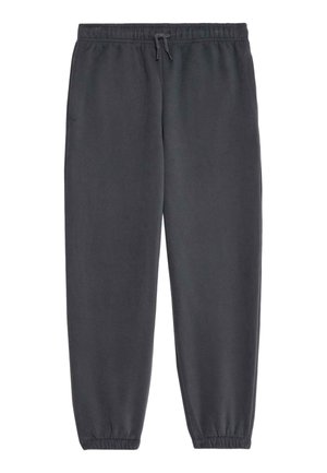 To børn iført mørkegrå hættetrøjer og matchende joggingbukser med hvide sneakers, stående mod en neutral baggrund.