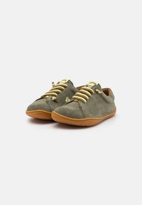 Scarpe in suede verde con lacci gialli a contrasto, punta arrotondata, suola in gomma flessibile e dettagli di cucitura minimi.