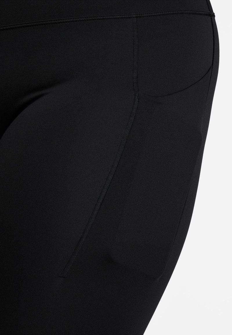 Leggings deportivos negros con una textura suave, diseño ajustado y un detalle de bolsillo lateral. Las costuras son visibles a lo largo de las uniones.