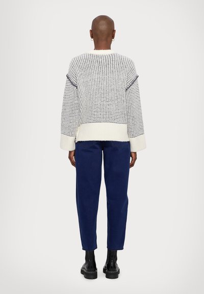 Knitted sweater in white and navy check pattern, loose fit, ribbed cuffs and hem. Paired with dark blue straight-leg jeans and black boots.