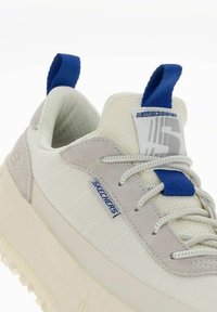 Sneakers marki Skechers w kolorze białym i jasnoszarym, z teksturowanej tkaniny, wyściełanym kołnierzem, niebieskimi akcentami oraz grubą beżową podeszwą.
