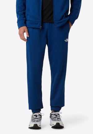Blue athletic pants made of textured fabric with elastic cuffs, featuring a small white logo on the side and a relaxed fit.