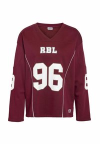 Bordo dukserica dugih rukava s bijelim detaljima, sadrži natpis "RBL" iznad broja 96, a broj 86 na rukavima. Dizajn s V izrezom.