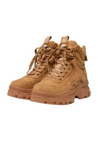 Zapatillas altas de ante marrón con suelas de goma gruesa, cordones en contraste y dos lazos en el tobillo para un ajuste seguro.