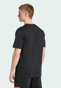 T-shirt en coton noir à manches courtes, avec un col rond et une conception des épaules sans couture. Simple et de couleur unie, texture lisse.