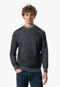 Maglione grigio a righe con una texture a coste, colletto rotondo e maniche raglan, abbinato a jeans scuri. Vestibilità classica e design informale.