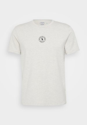 T-shirt de algodão cinza claro com decote redondo. Apresenta um logotipo circular bordado no peito com texto ao redor de uma silhueta.