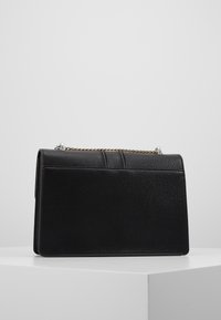 Borsa a mano in pelle nera con un design strutturato, caratterizzata da una superficie texturizzata, una tracolla in catena dorata e dettagli di cucitura sottili.