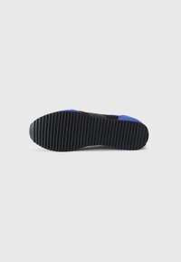 Black sneaker outsole with textured ridges, featuring a blue accent near the heel. Rubber material for traction and durability.