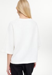 Maglione bianco lavorato a maglia con maniche corte, scollo rotondo e una texture morbida. Presenta una vestibilità comoda e un orlo dritto.