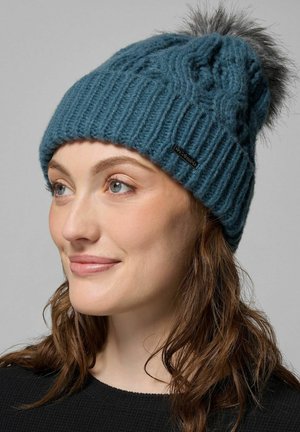 Beanie lavorato a maglia in teal con un motivo strutturato e una pompon in pelliccia grigia sulla sommità. Presenta un piccolo logo sul lato.