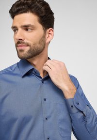 Blauwe shirt met een patroon, met een button-down kraag, lange mouwen en een borstzak. Voorzien van contrasterende knopen en een textuurdesign.